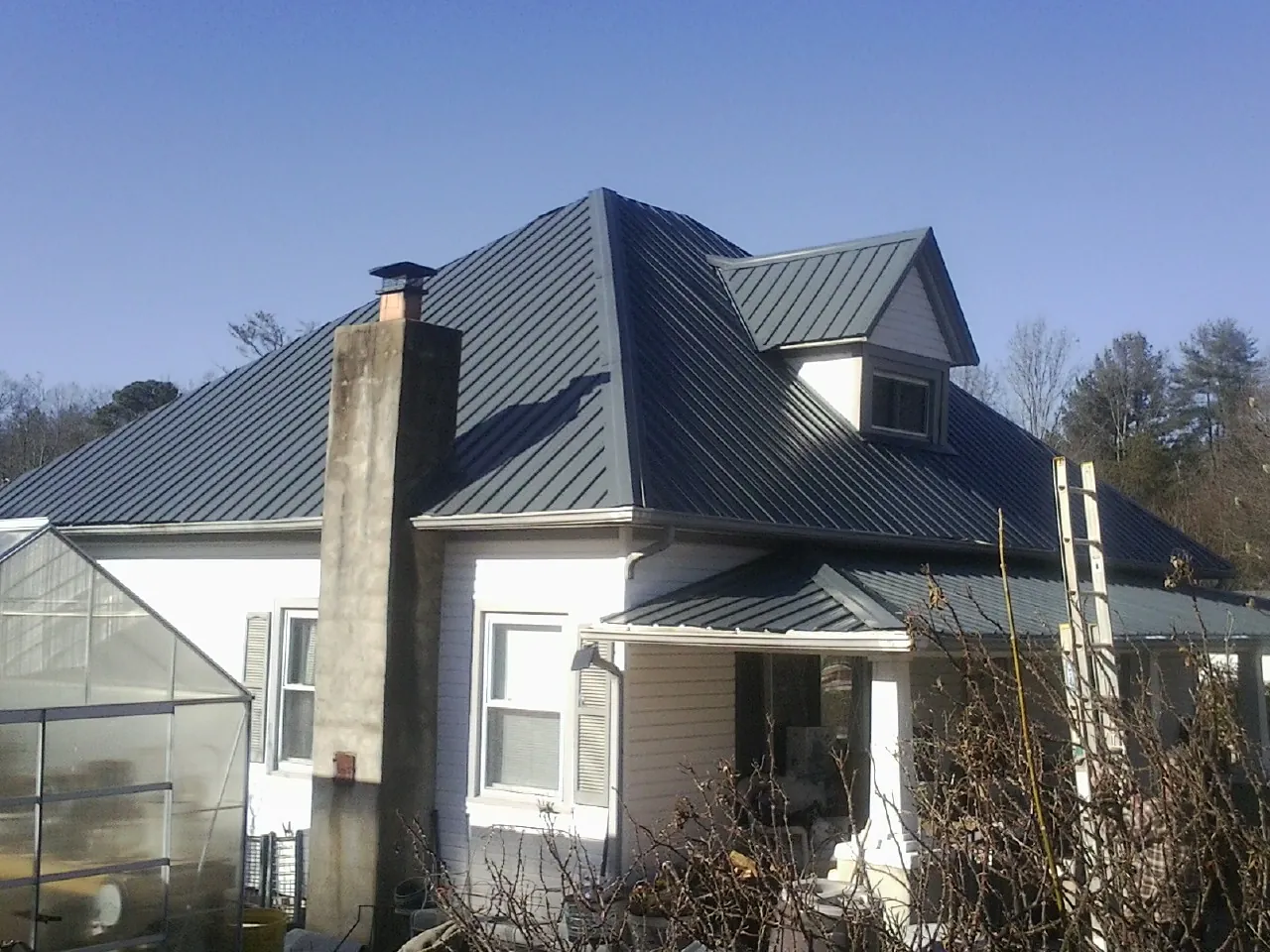 Dark blue standing seam metal roof on a white farmhouse with dormer — Slate & Tile Roof Repair by Roofing Brothers in Calabasas