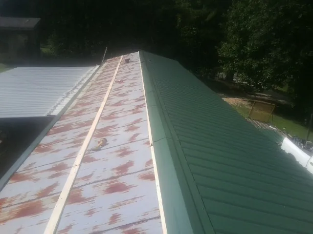 Old rusted panels beside newly installed green metal roofing — Wind Damage Roof Repair by Roofing Brothers in Calabasas