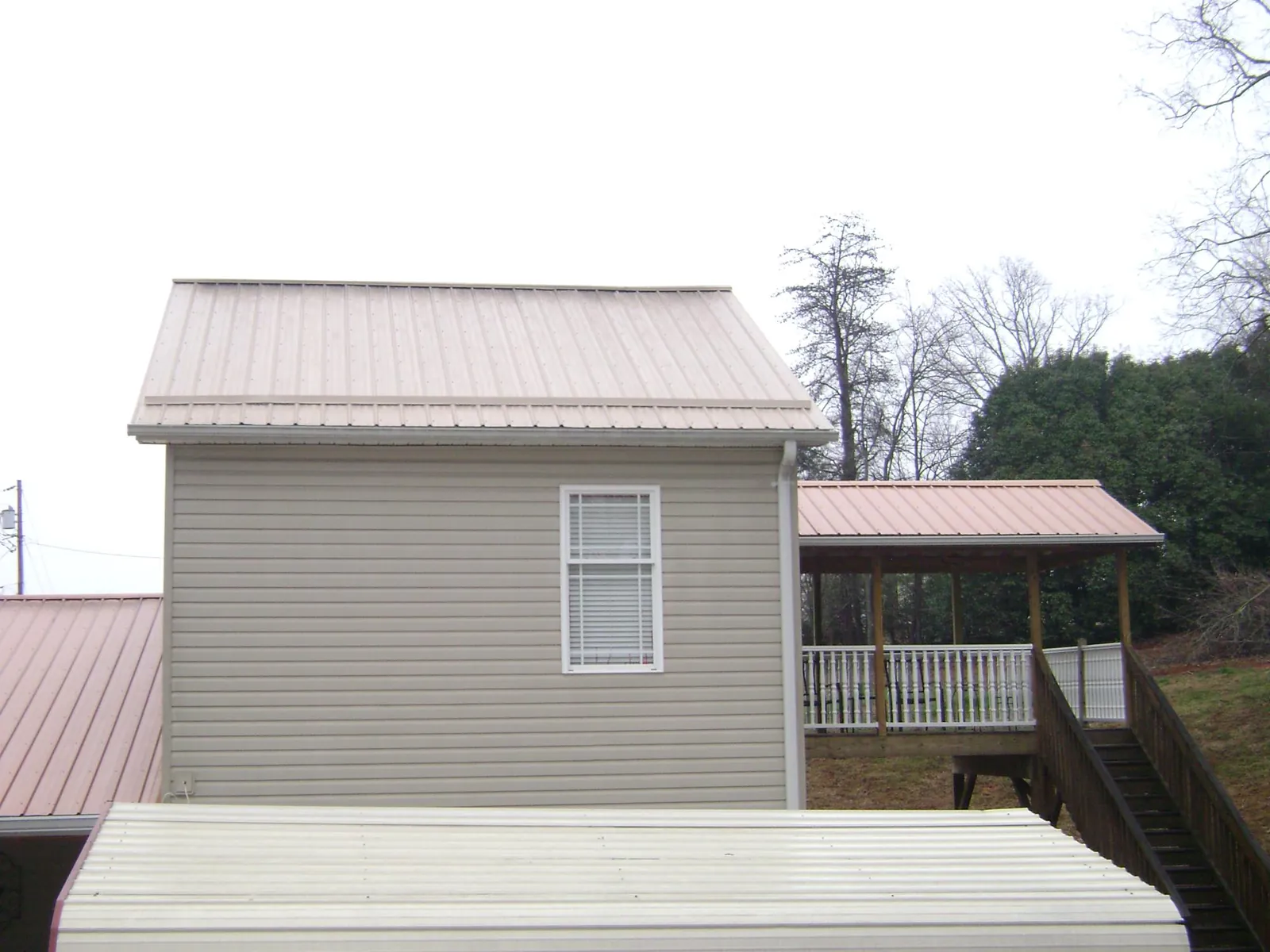 Tan metal roofs on a two story addition and attached porch, from a Roof Replacement job in Calabasas