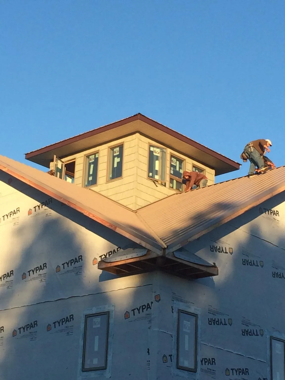 Roofers working around a rooftop cupola on a new metal roof at sunset — Roof Waterproofing in Calabasas by Roofing Brothers